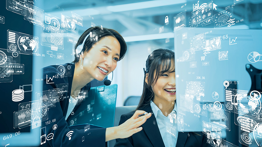 Duas mulheres olhando para uma tela em segundo plano. Sobreposição de pctogramas em primeiro plano representando técnologia.